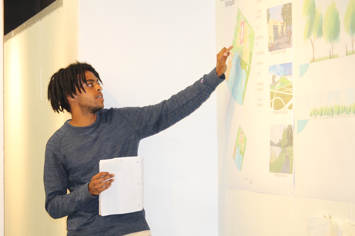 student pointing to plan on wall